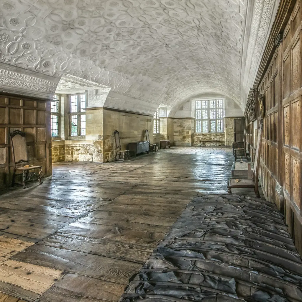 Oak-panelled long gallery with ornate plasterwork ceiling and leaded windows