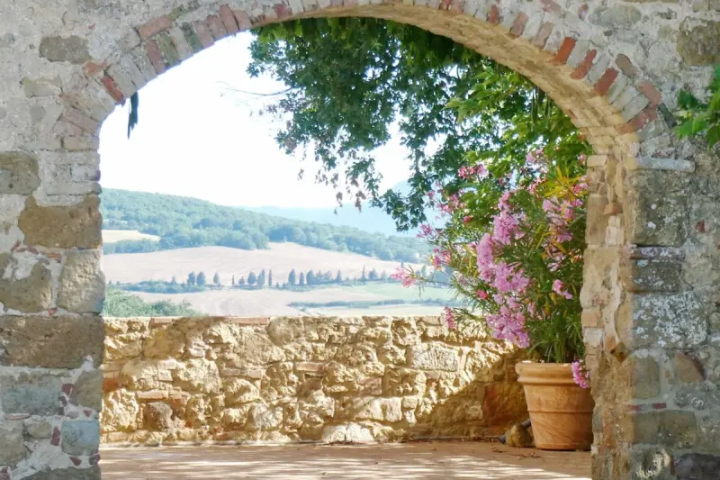 View through a stone archway over Tuscan hills, oleander in bloom
