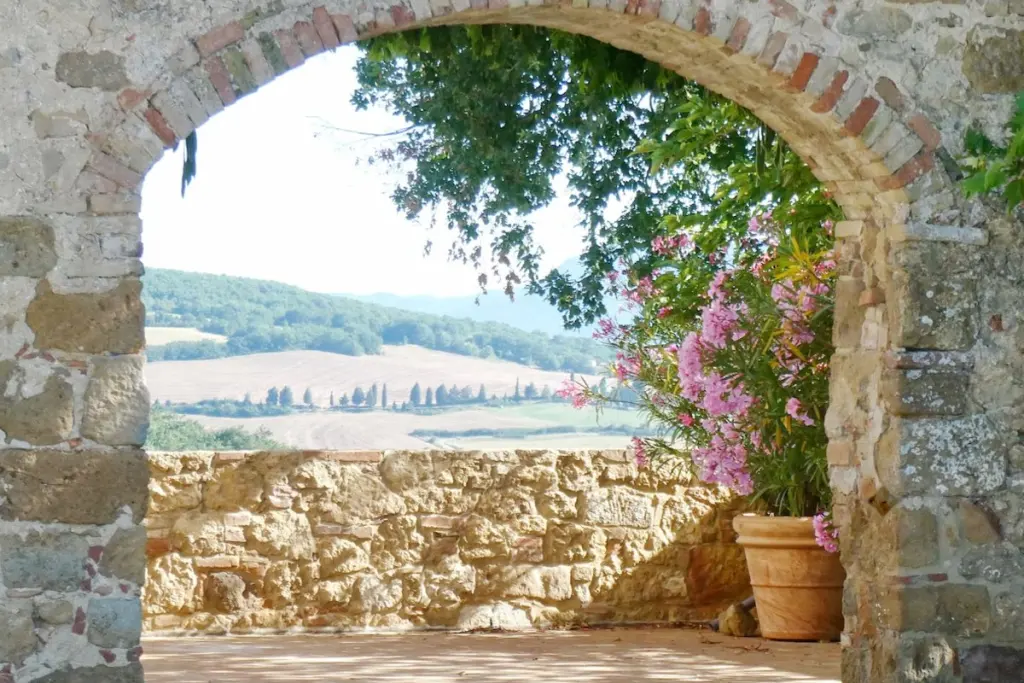 View through a stone archway over Tuscan hills, oleander in bloom
