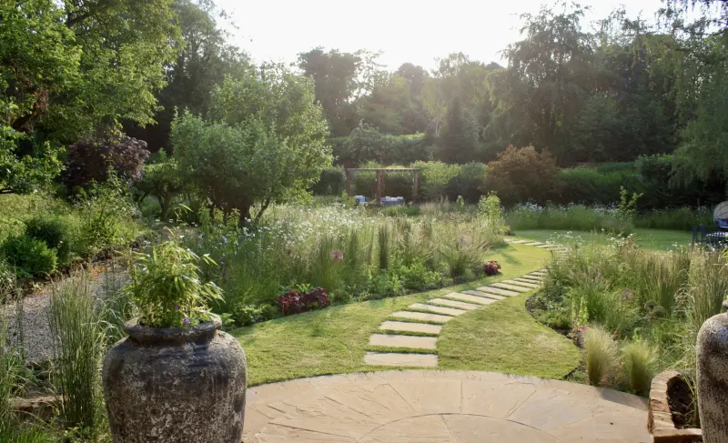 Evening light over a garden of stepping stones, grasses and meadow planting