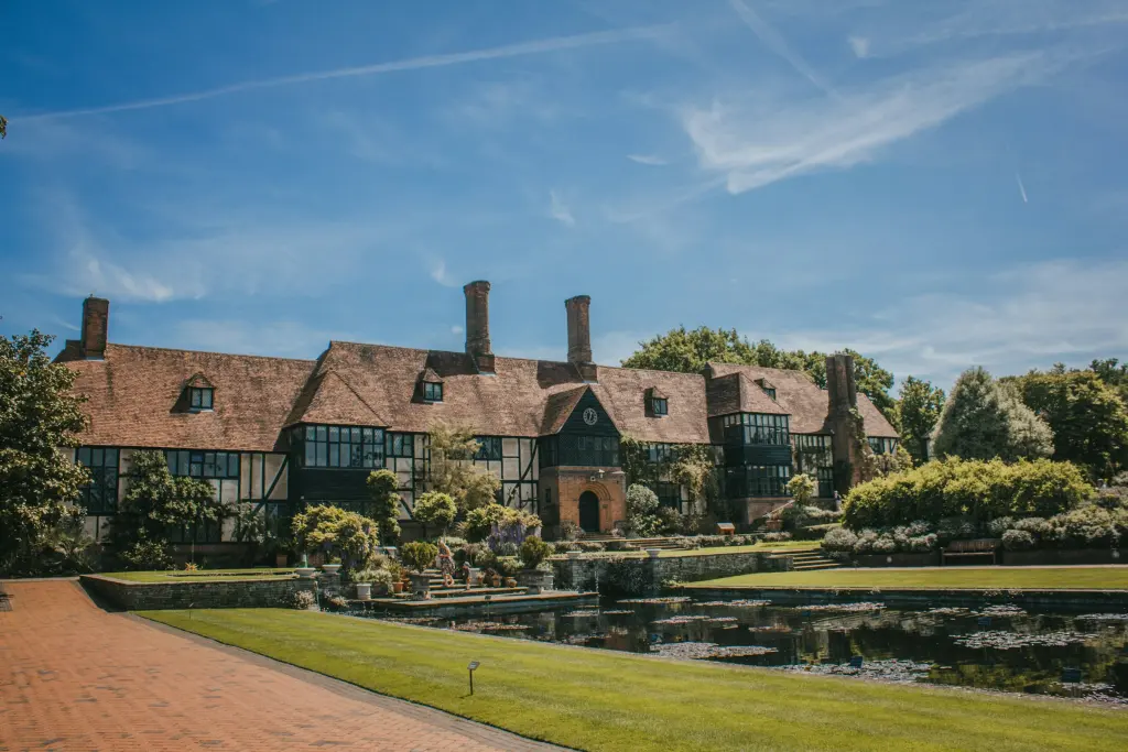Half-timbered English manor house beside a lily pond on a summer day
